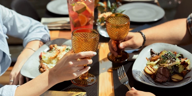 兩個人同桌吃飯，並且一同舉起杯子乾杯慶祝。